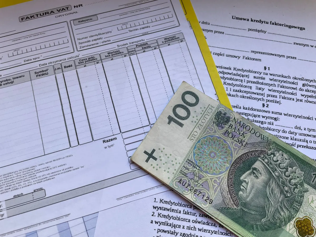 A paper Polish VAT invoice form and a 100 zloty banknote